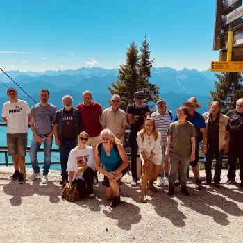 Gruppe von Menschen auf einem Berg mit Alpenpanorame im Hintergrund